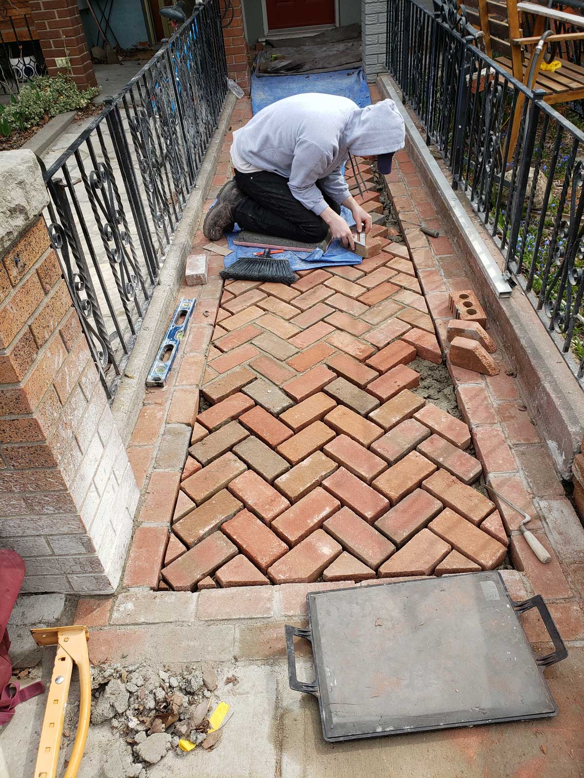 contractor laying bricks on pathway in front of home